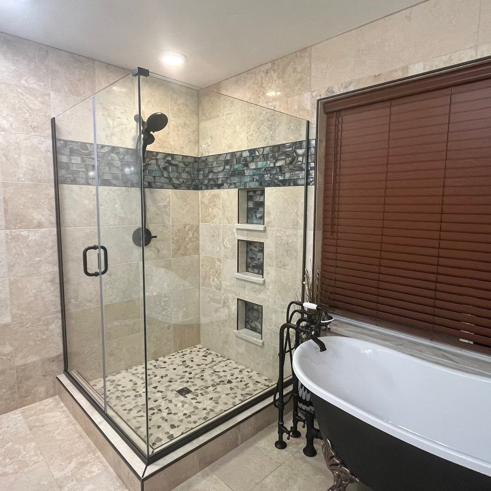 Frameless glass shower, pebble pan and a mosaic band