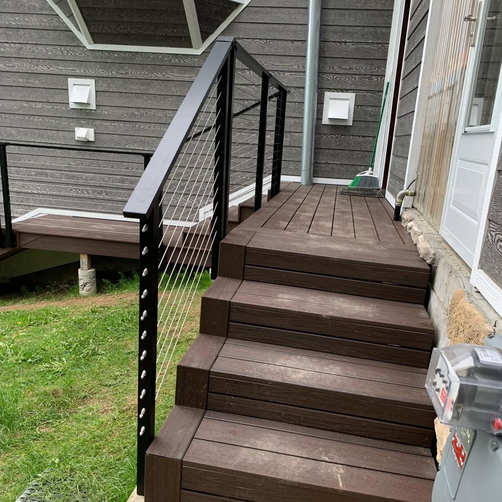 Composite deck stairs, black posts and cable infill running up to the door