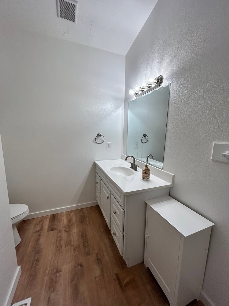 Half bath with a new vanity, mirror and plank floor