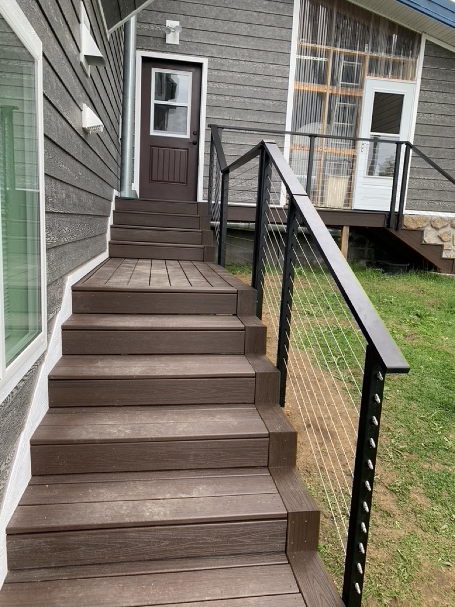 Composite deck steps with cable railing running down to a lawn