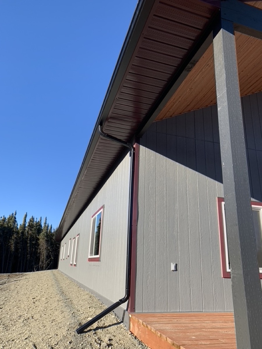 A sided corner with trim detail and a gutter run against open sky