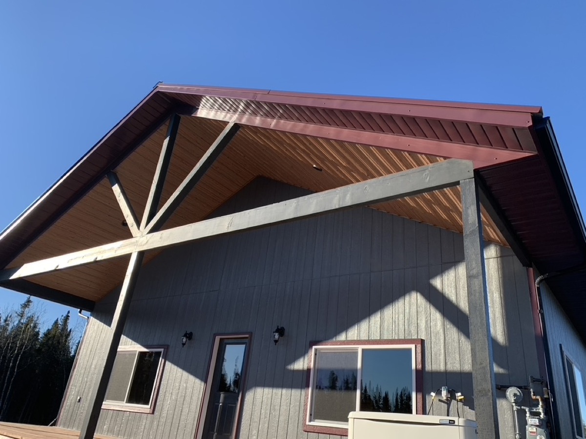 A timber truss entry canopy over a door on a sided building